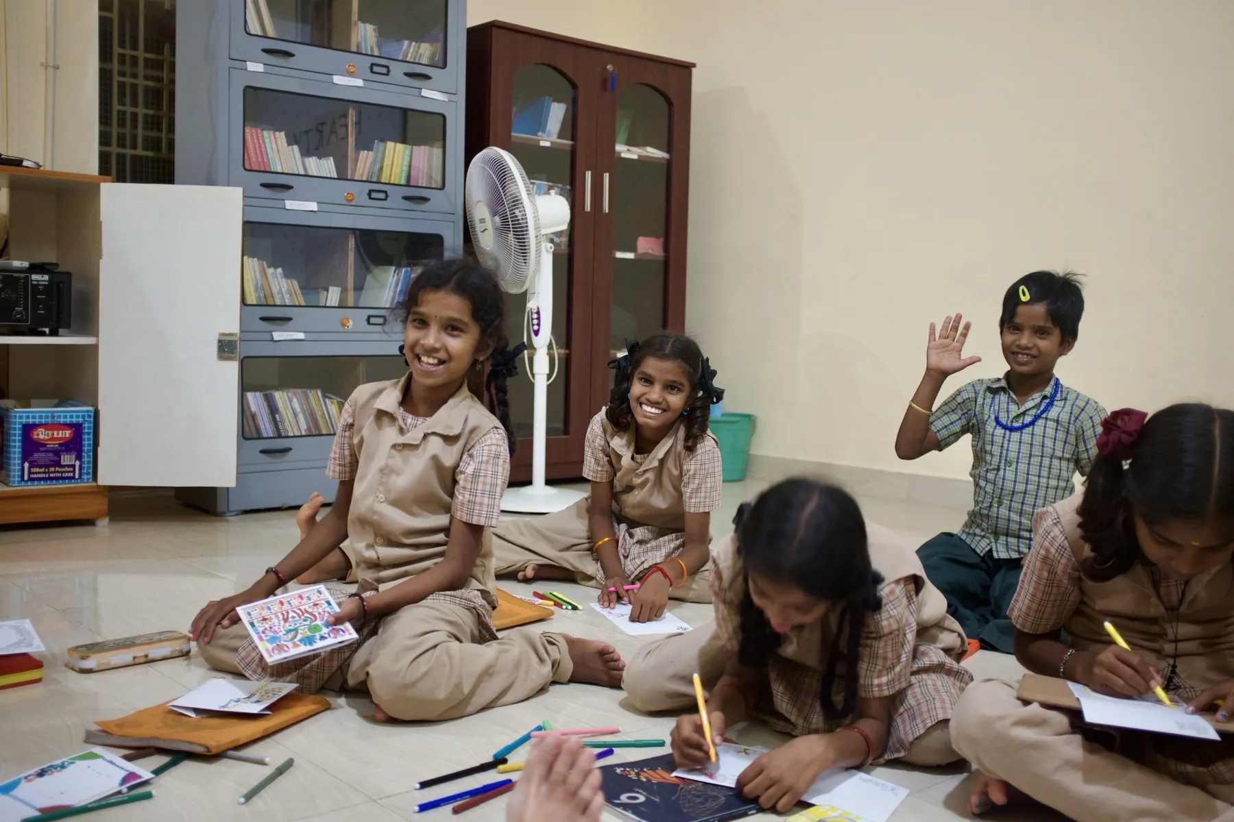 Ragazze sedute per terra in biblioteca mentre disegnano e colorano